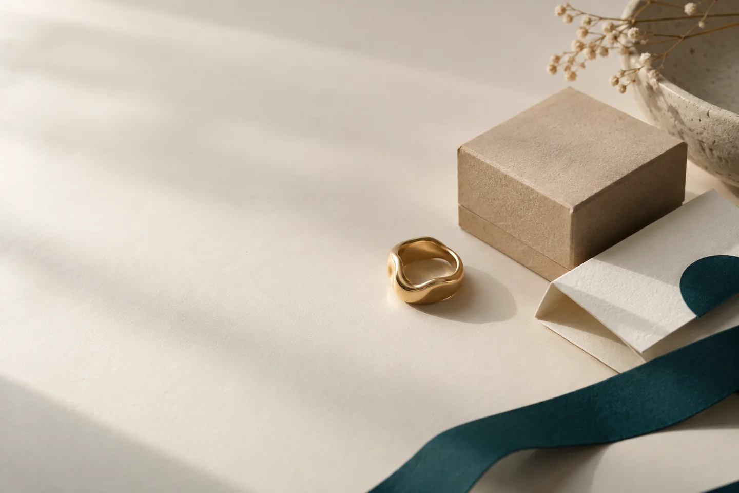 Anello, confezione e carta su un piano da lavoro: un richiamo alla cura di un e-commerce di gioielleria.